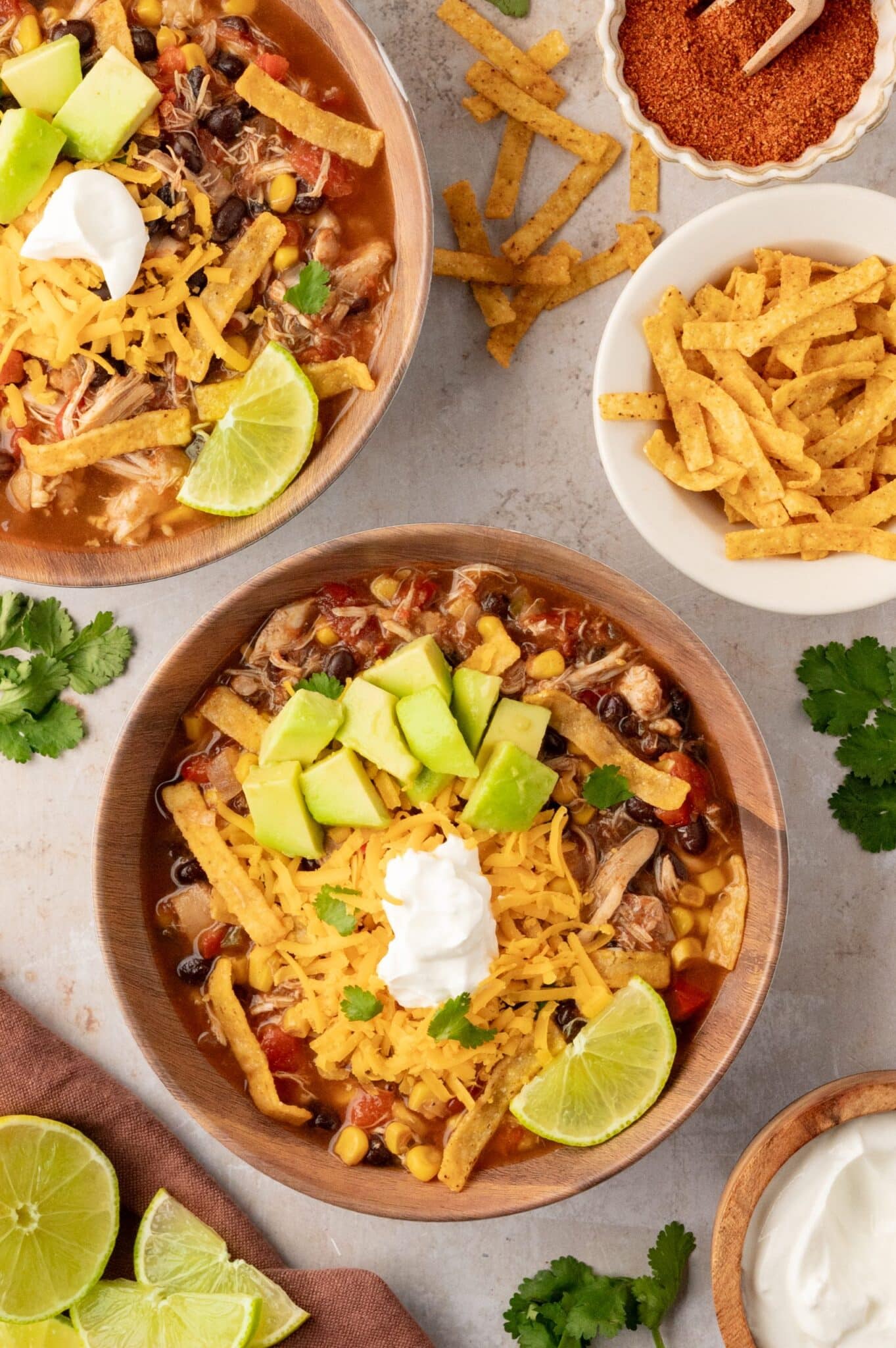 A bowl of chicke tortilla soup with cheese, avaocade, sour cream and cheese