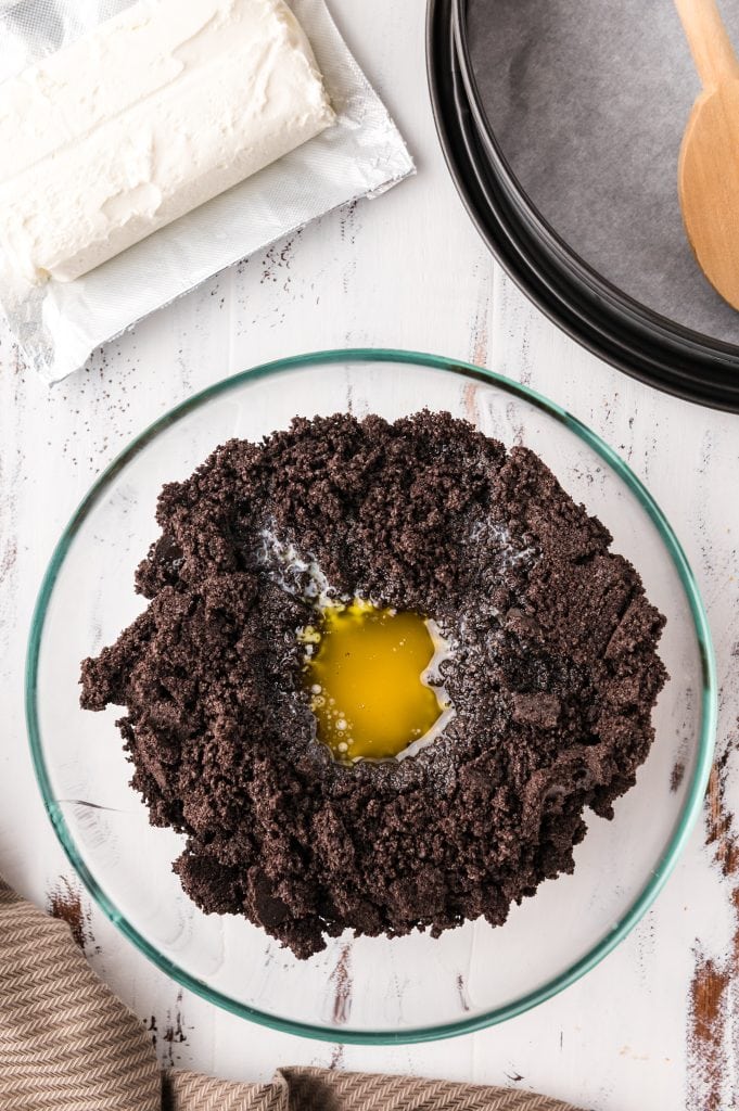 crushed oreos and melted butter in a bowl