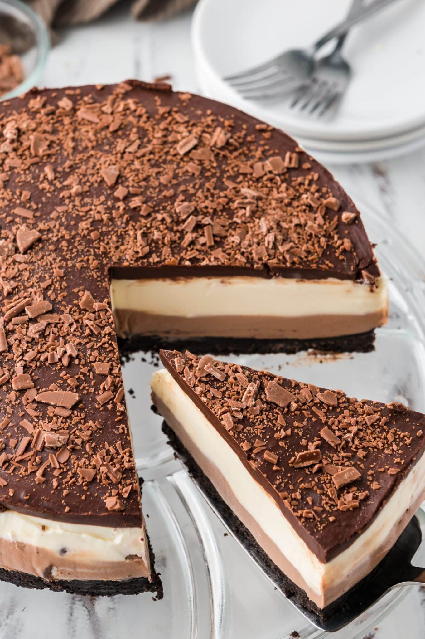 A slice of no bake layered chocolate cheesecake being removed from the cake