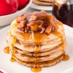 A stack of Apple Pancakes with apples and syrup.