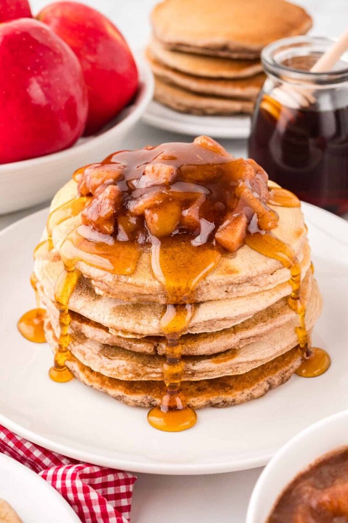 A stack of Apple Pancakes with apples and syrup.