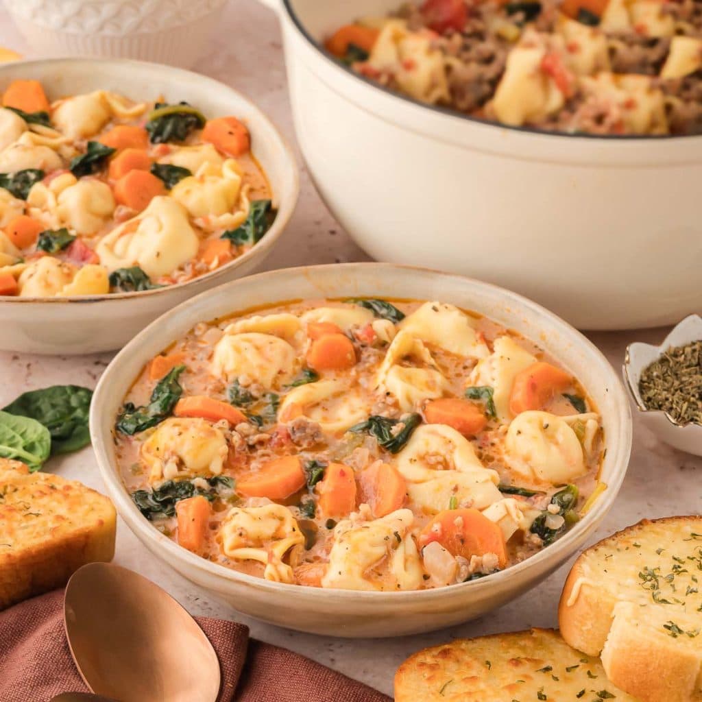 Front view of Cooked Creamy Tortellini Soup with a spoon.