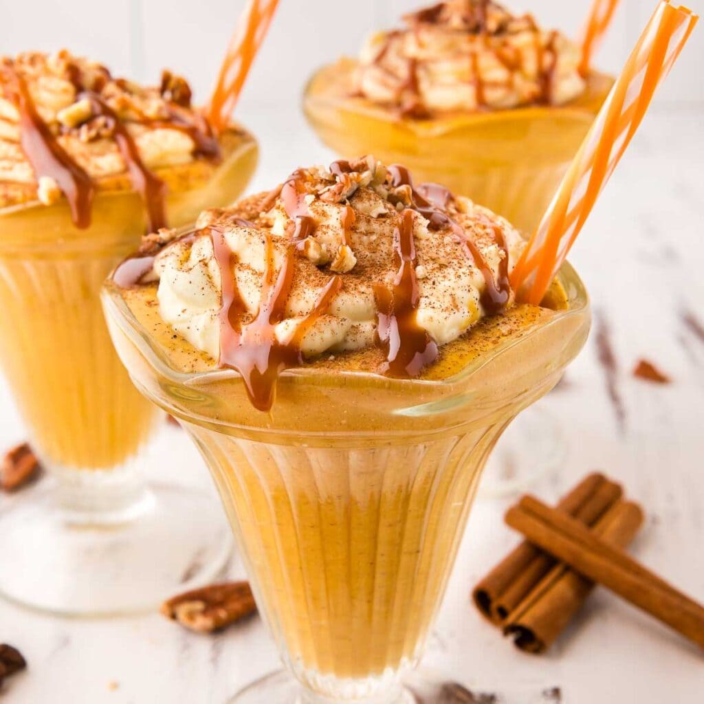 Pumpkin Milkshake with caramel saucecand an orange straw.