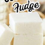 A close-up of thick white coconut fudge squares stacked with shredded coconut on top.