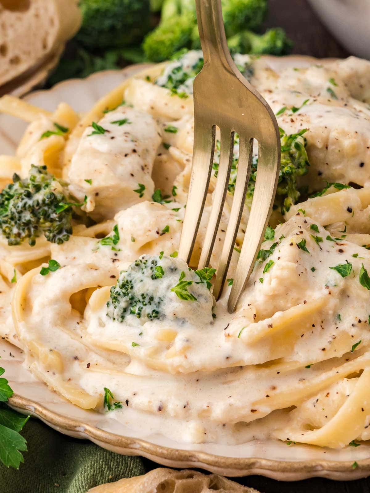 Up close of a fork twisting some Chicken and Broccoli Alfredo.