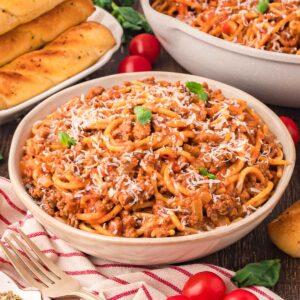 A bowl of Spaghetti with some parmasean cheese and basil.