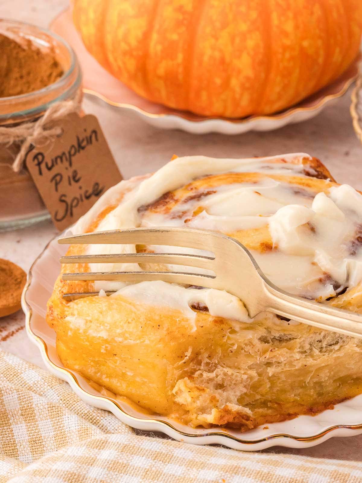 Up close of a fork cutting into pumpkin cinnamon rolls.