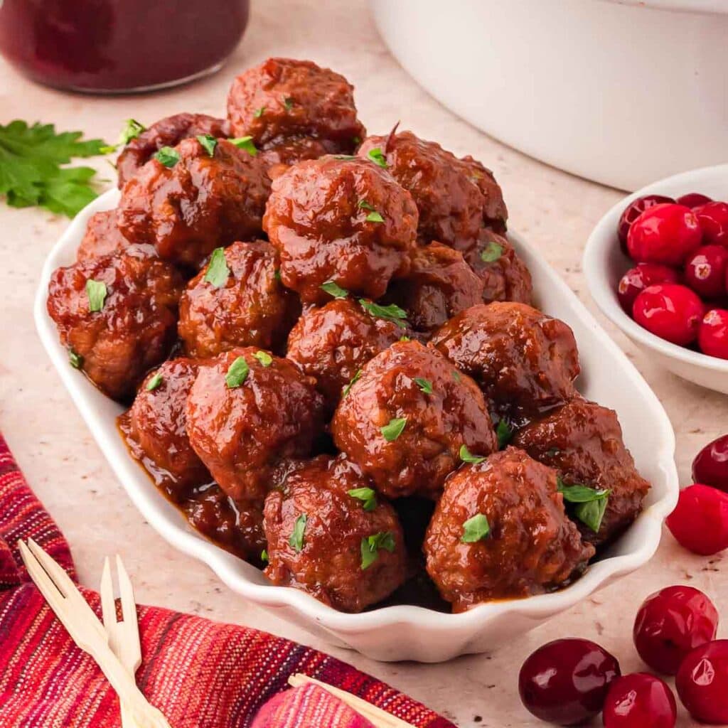 Cranberry meatballs on a serving dish with tooth picks beside them.