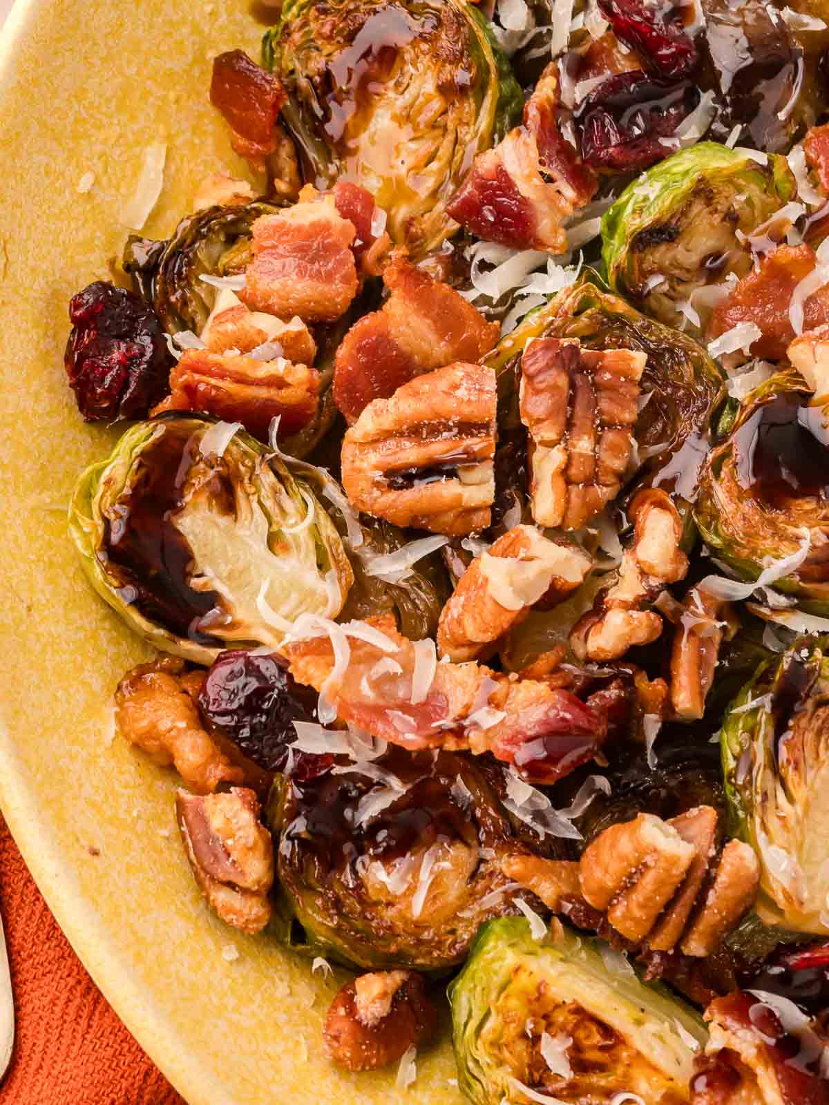 Up close of Warm Brussels Sprout Salad with balsamic glaze in a yellow bowl.