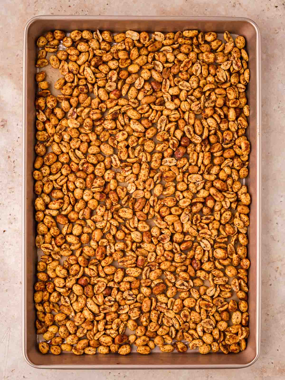 An oven tray with cooked spiced peanuts.