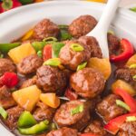 Spoonful of fully cooked sweet and sour meatballs in a slow cooker.