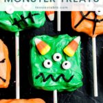 Green monster treat with candy eyes and candy corn horns on a lollipop stick surrounded by orange monster treats by Tessie's Table.