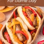 Two slow cooker bratwurst subs loaded with peppers and onions on a wooden tray, an easy game day dinner by Tessie's Table.