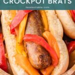 Close-up of a slow cooker bratwurst in a bun topped with red and yellow peppers by Tessie's Table.