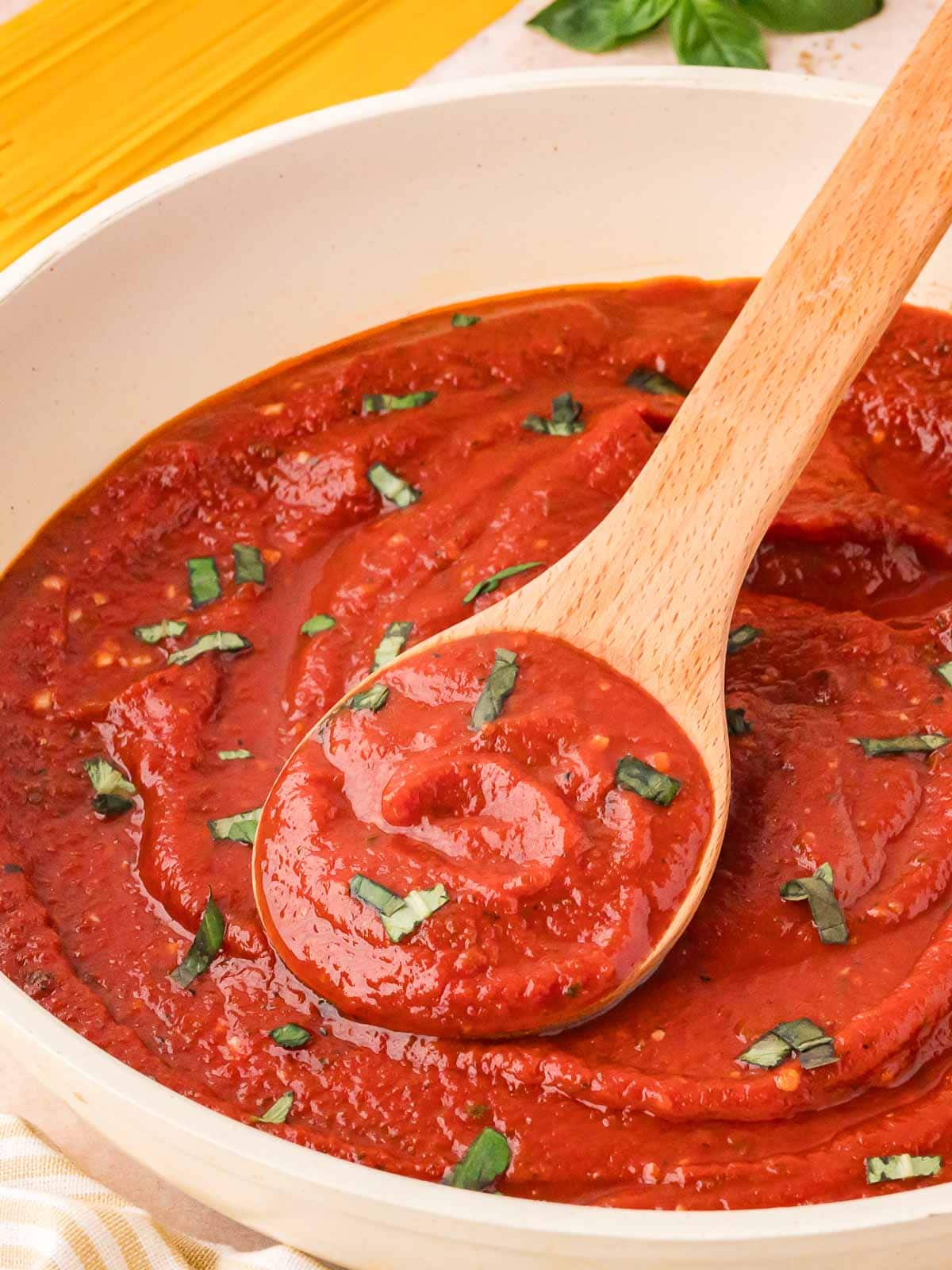 Homemade Marinara Sauce in a pan with a wooden spoon.