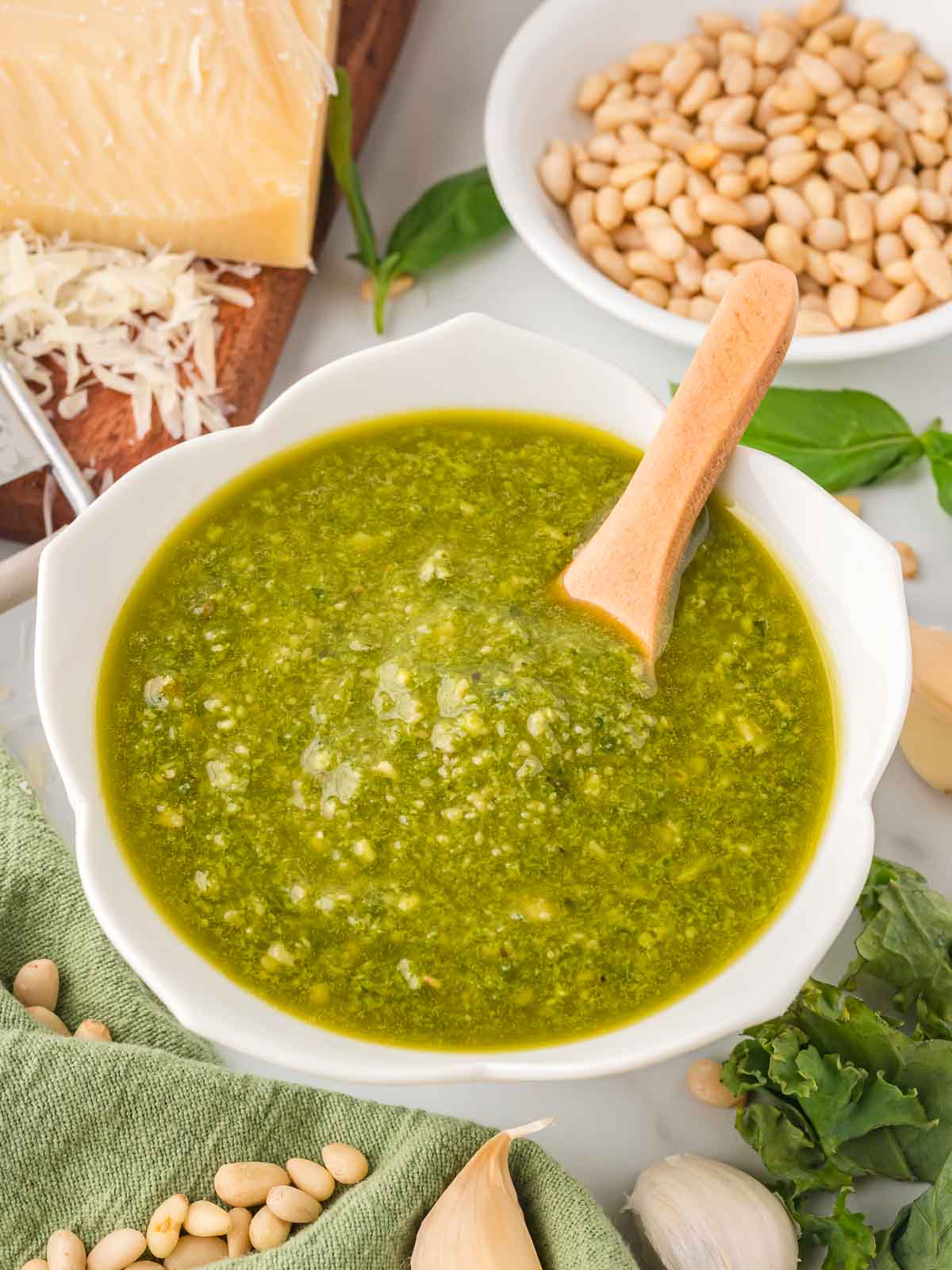 Kale Pesto in a white bowl with a wooden spoon.