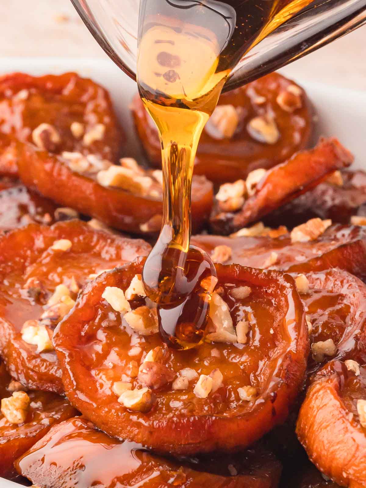 Maple Syrup being drizzled over Maple Roasted Sweet Potatoes.