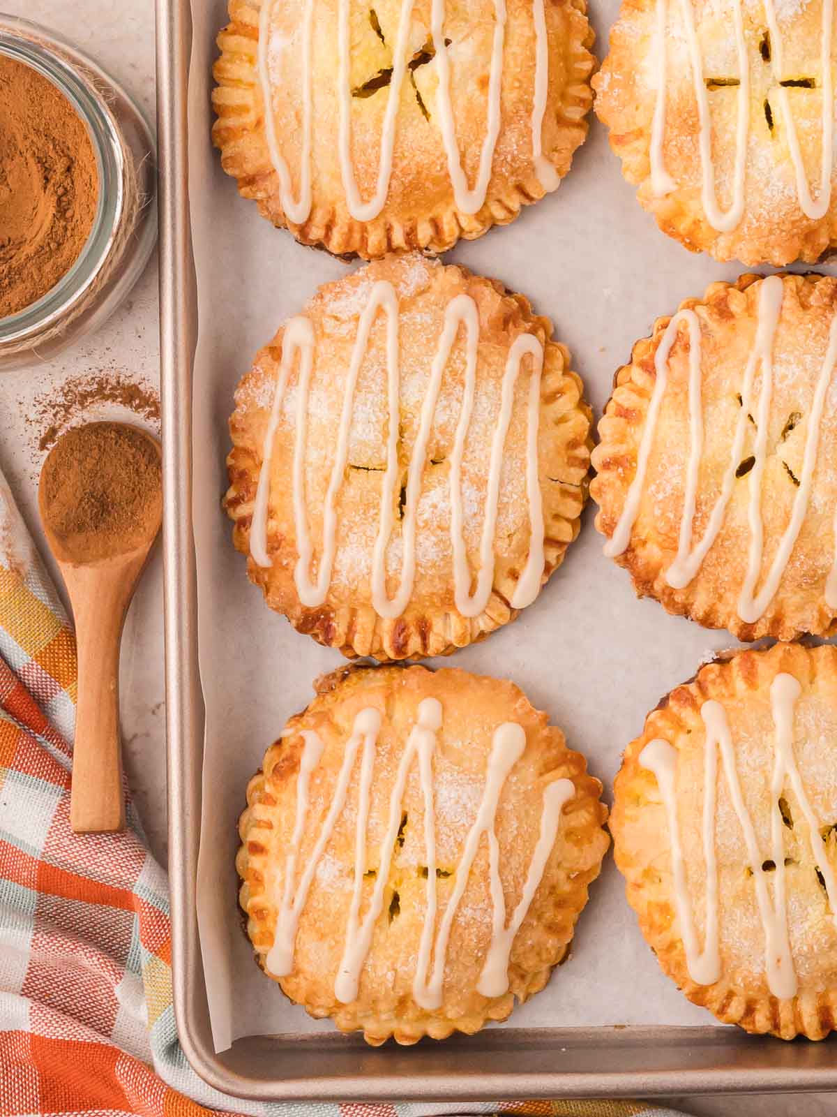 Pumpkin hand pies with maple glaze on a baking sheet.