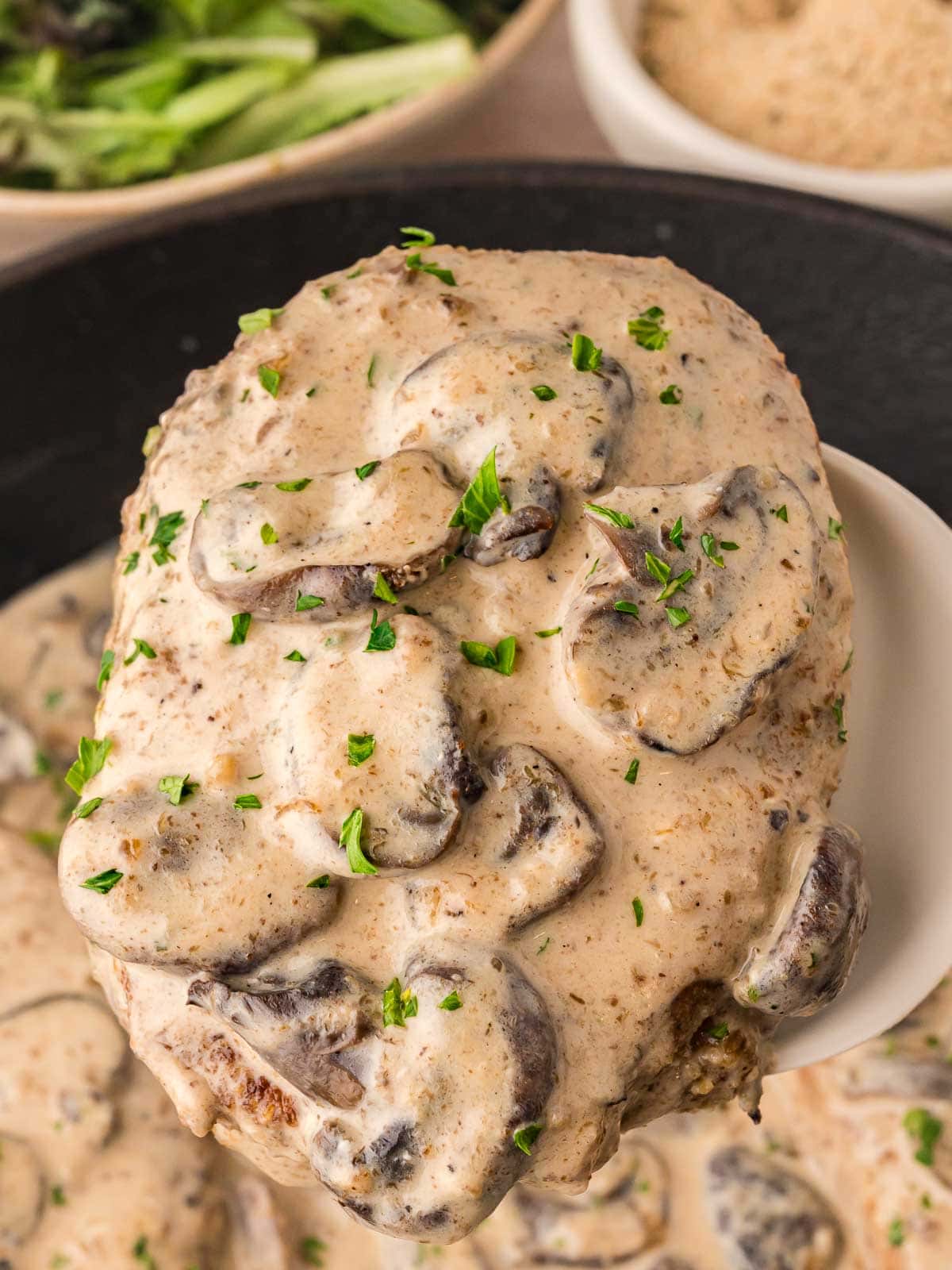 Smothered Pork Chop getting lifted out of the pan.