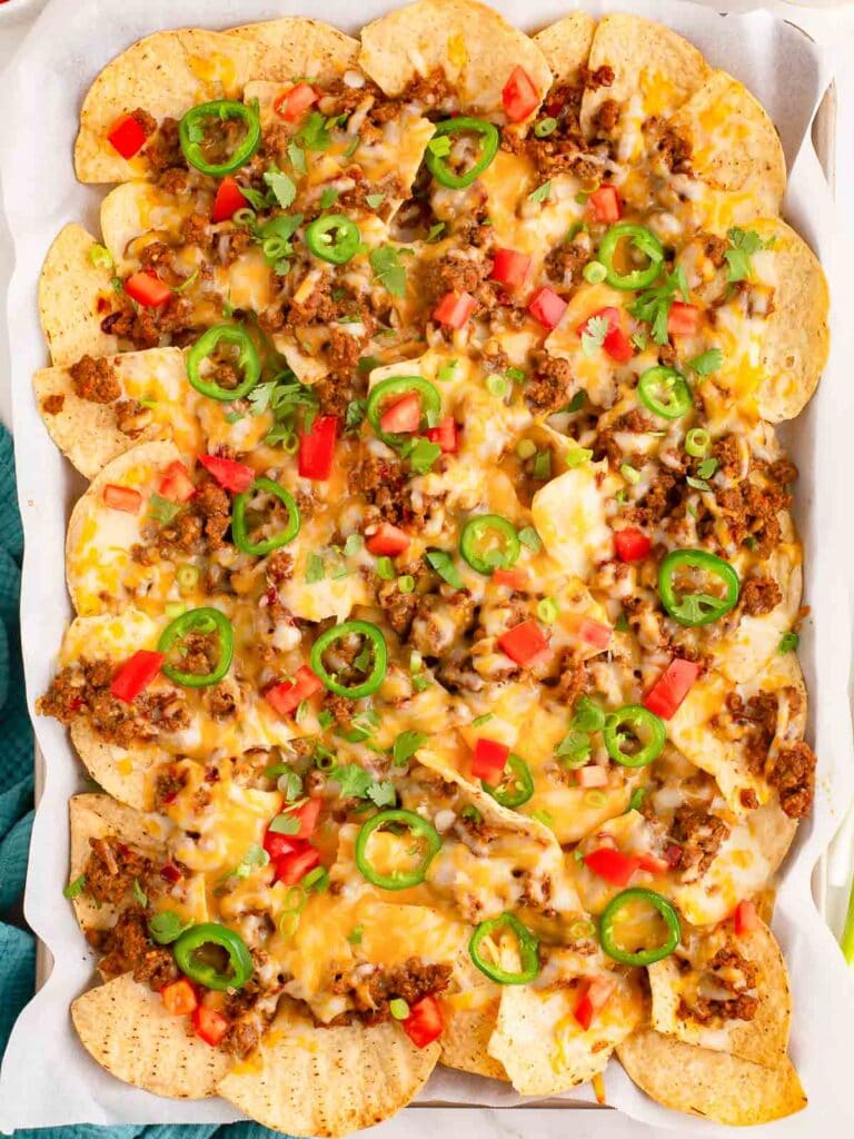 Overhead shot of Beef Nachos in a tray with all the toppings after melting the cheese.