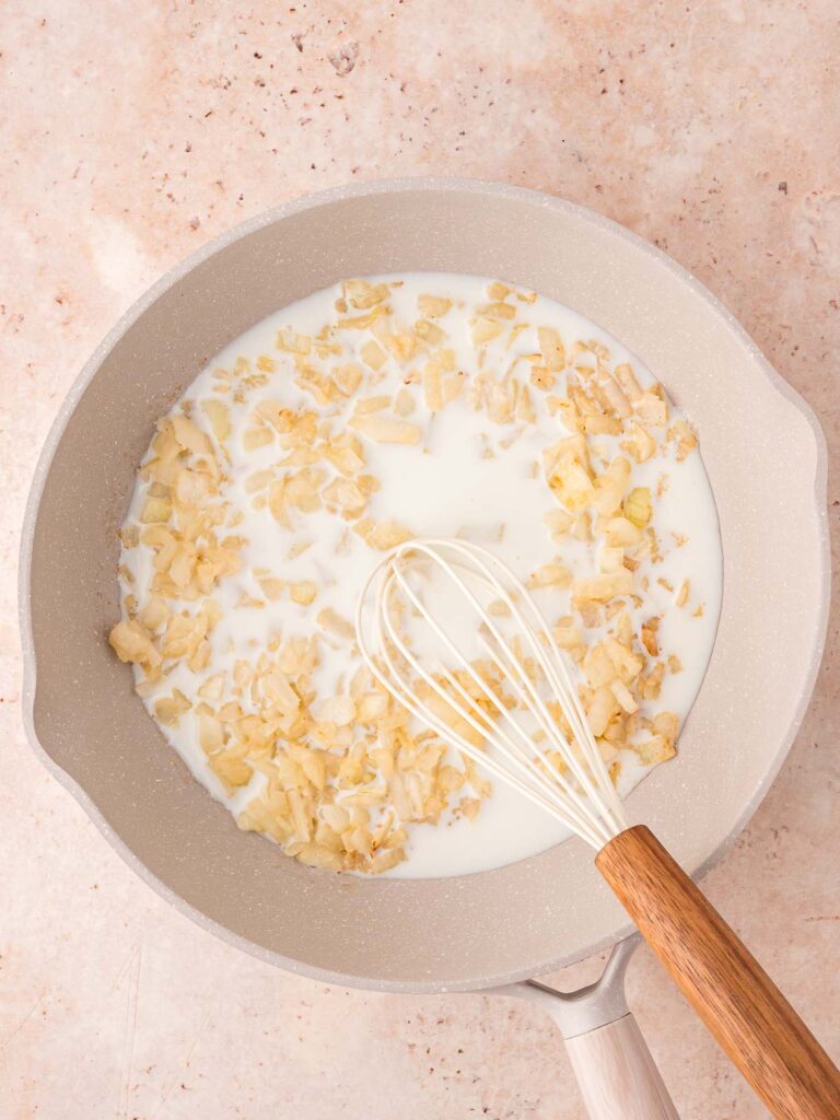 Milk pouredinto the pan with the onion and flour.