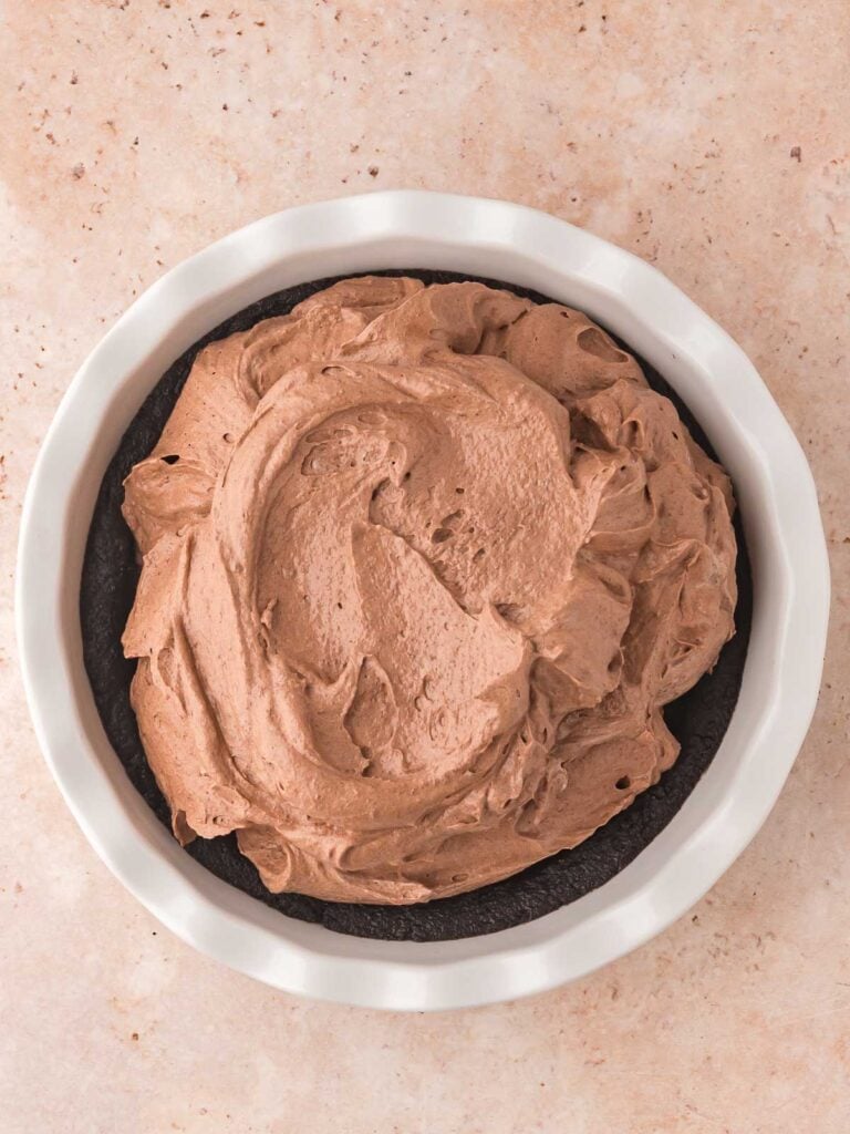 Adding the chocolate mixture to the Oreo crust in a pie dish.