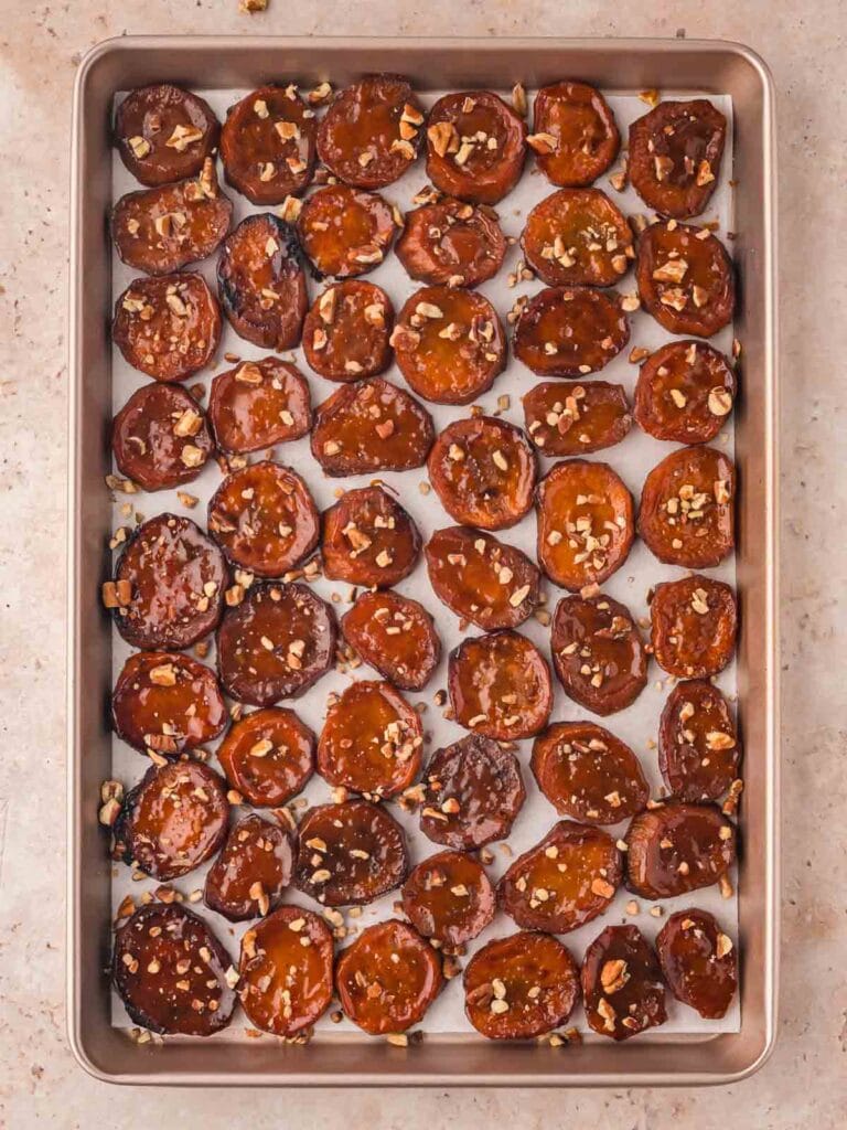 Maple Roasted Sweet Potatoes cooked on a baking tray with pecans on top.