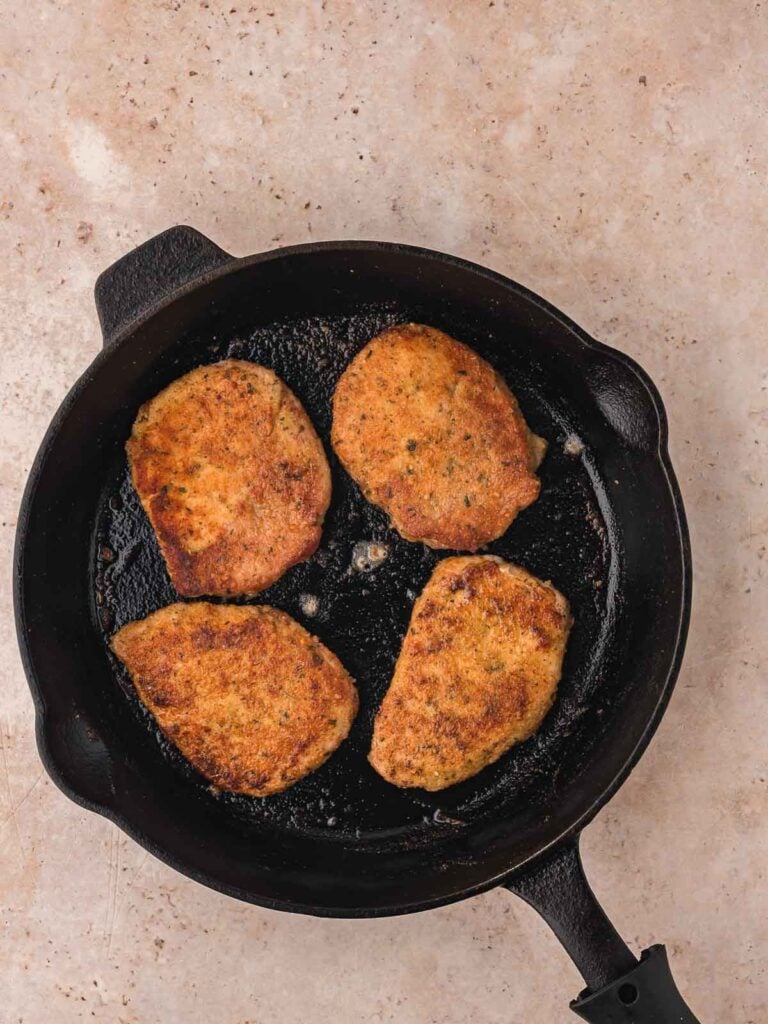 Parmesan Crusted Pork Chop in a cast Iron skillet.