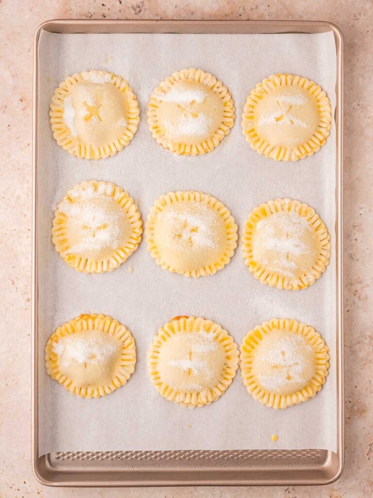 Uncooked Pumpkin Hand Pies on a baking tray.