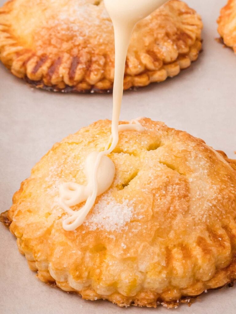 Maple glaze being drizzled onto Pumpkin Hand Pies.