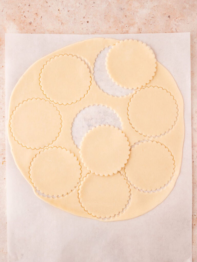 Pie crust with rounds cut out to make pumpkin hand pies.