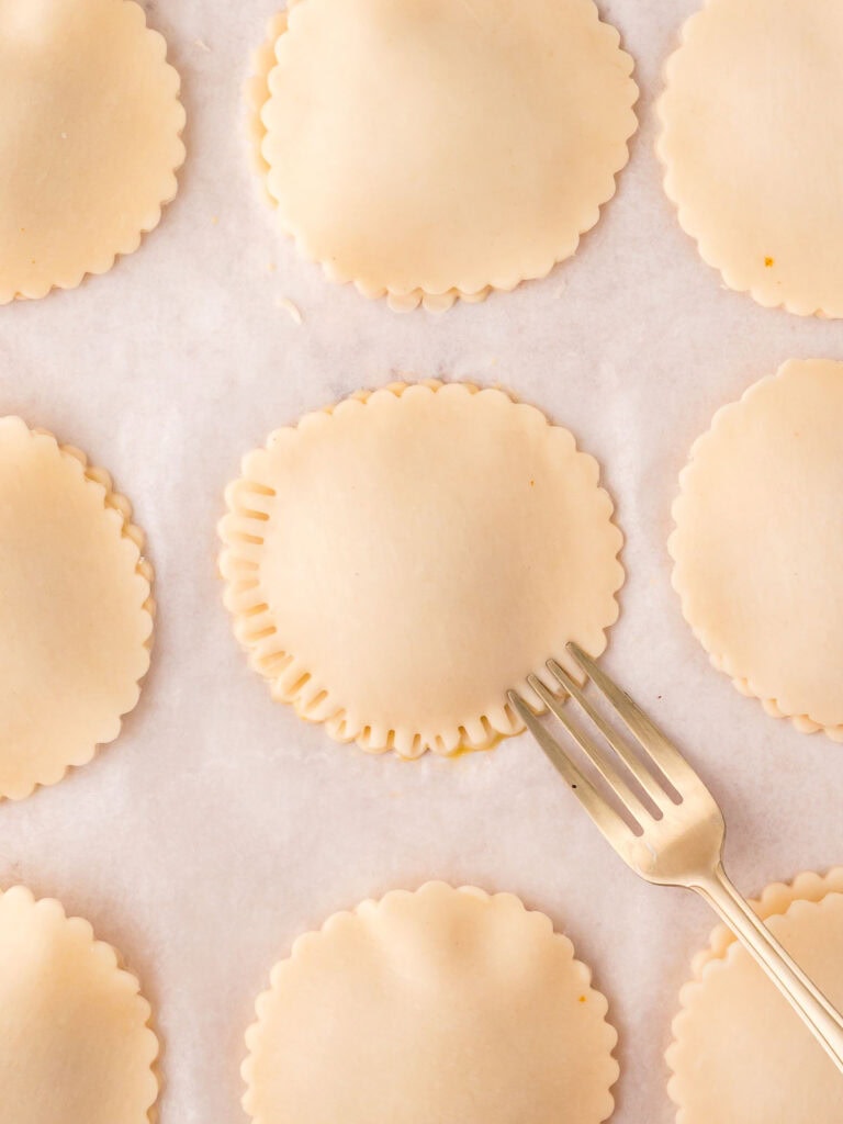 A fork crimping the edges of Pumpkin Hand Pies.