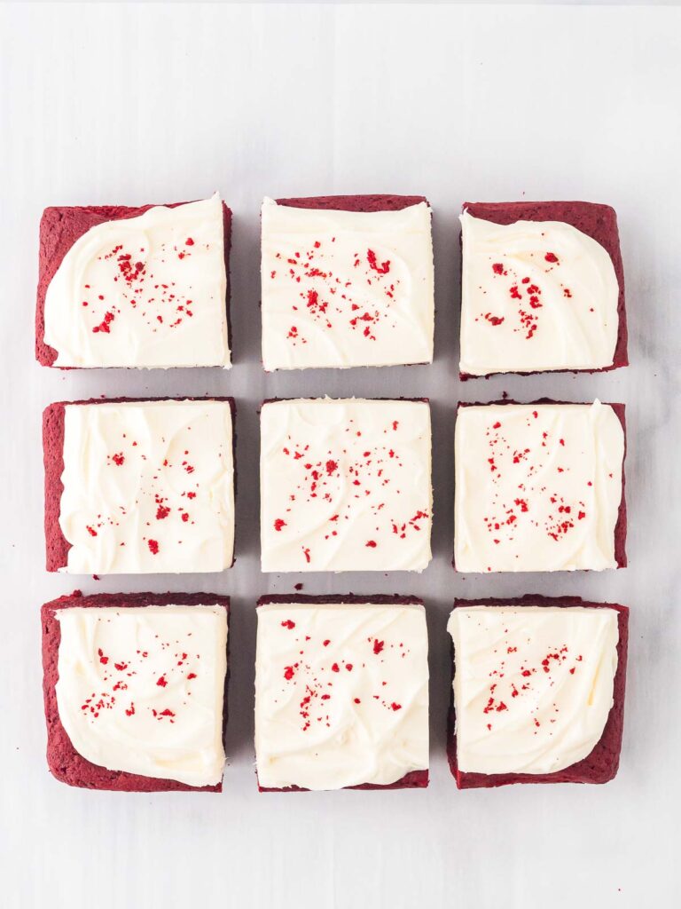 Red Velvet Brownies cut into 9 pieces with crumbs sprinkled on top.