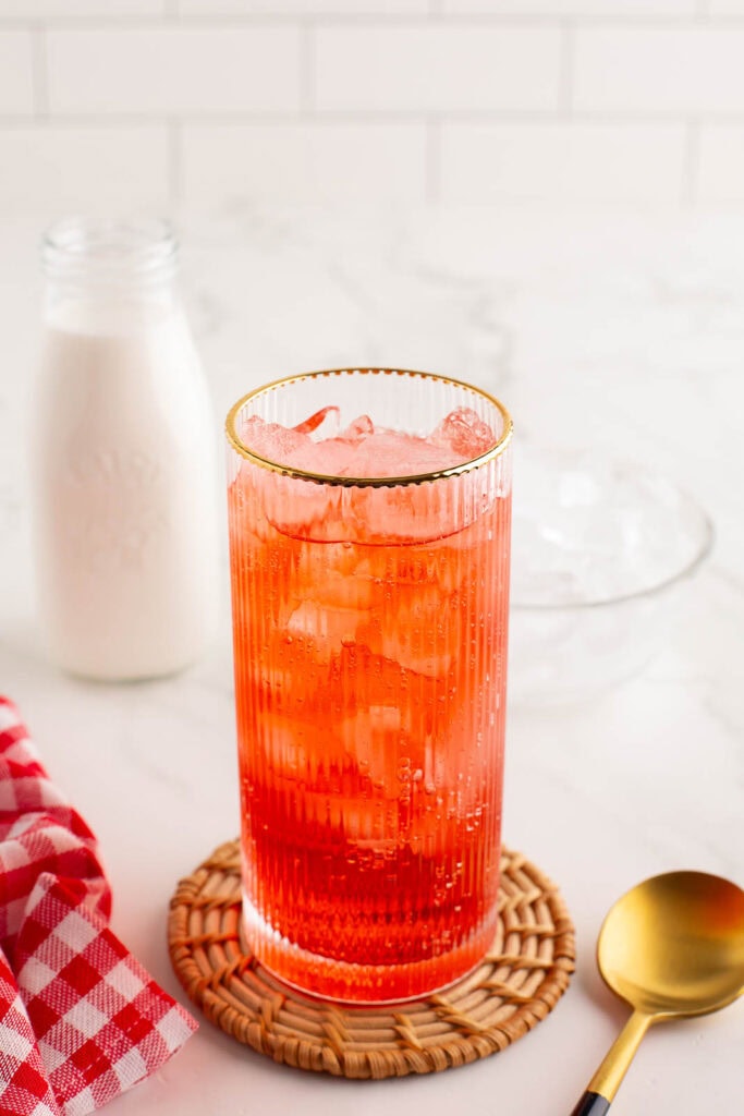 The club soda and strawberry syrup over ice.