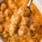 A spoon full of slow cooker butter chicken meatballs.