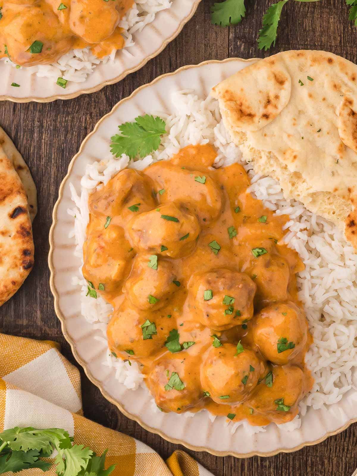 A plate with Slow Cooker Butter Chicken Meatballs and rice on it.