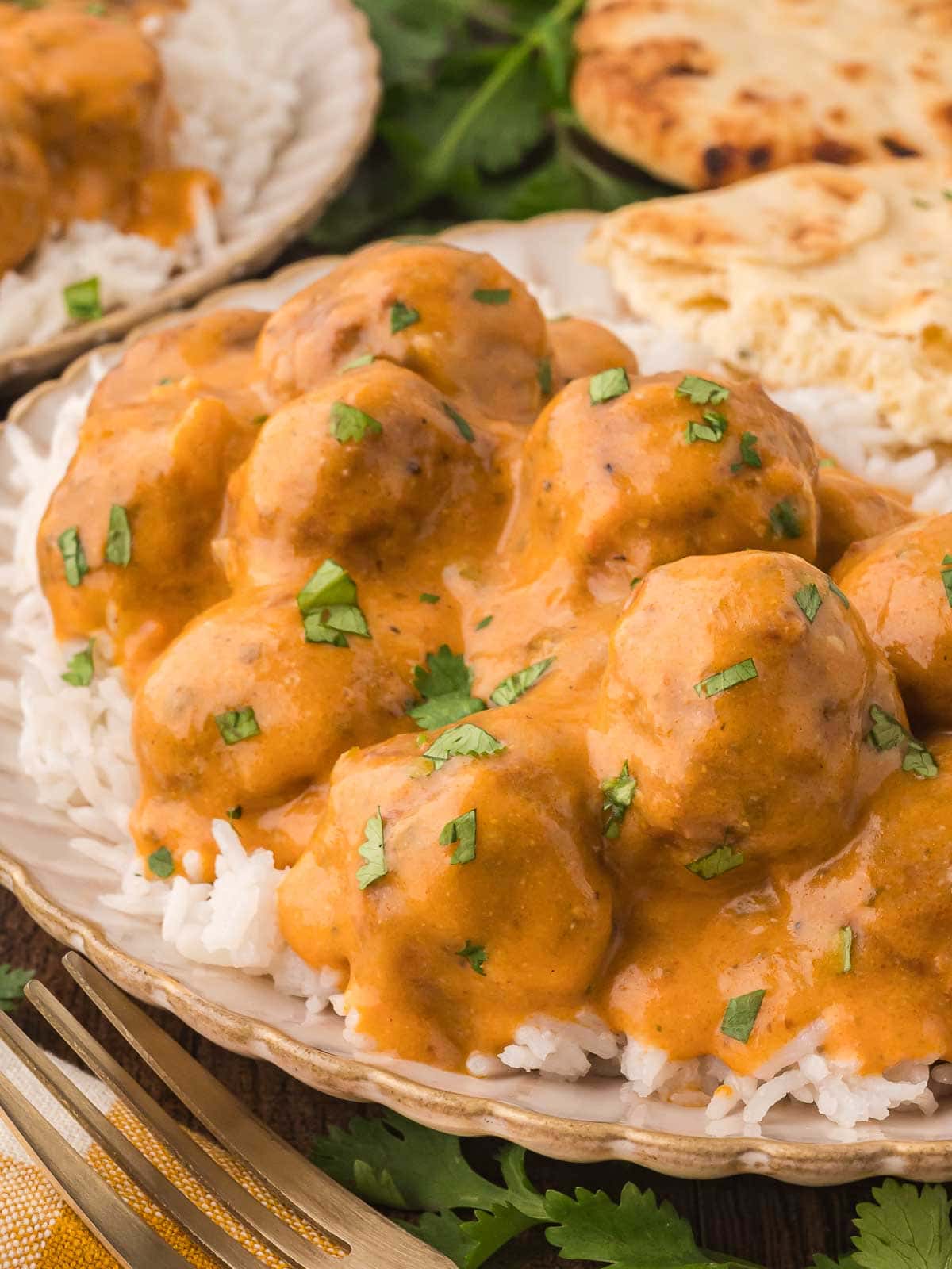 Slow Cooker Butter Chicken Meatballs on a plate with lots of sauce.