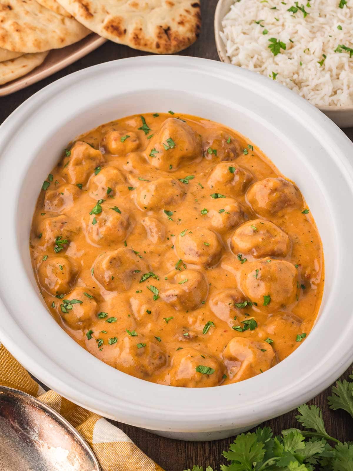 A white crock pot with Butter Chicken Meatballs inside.