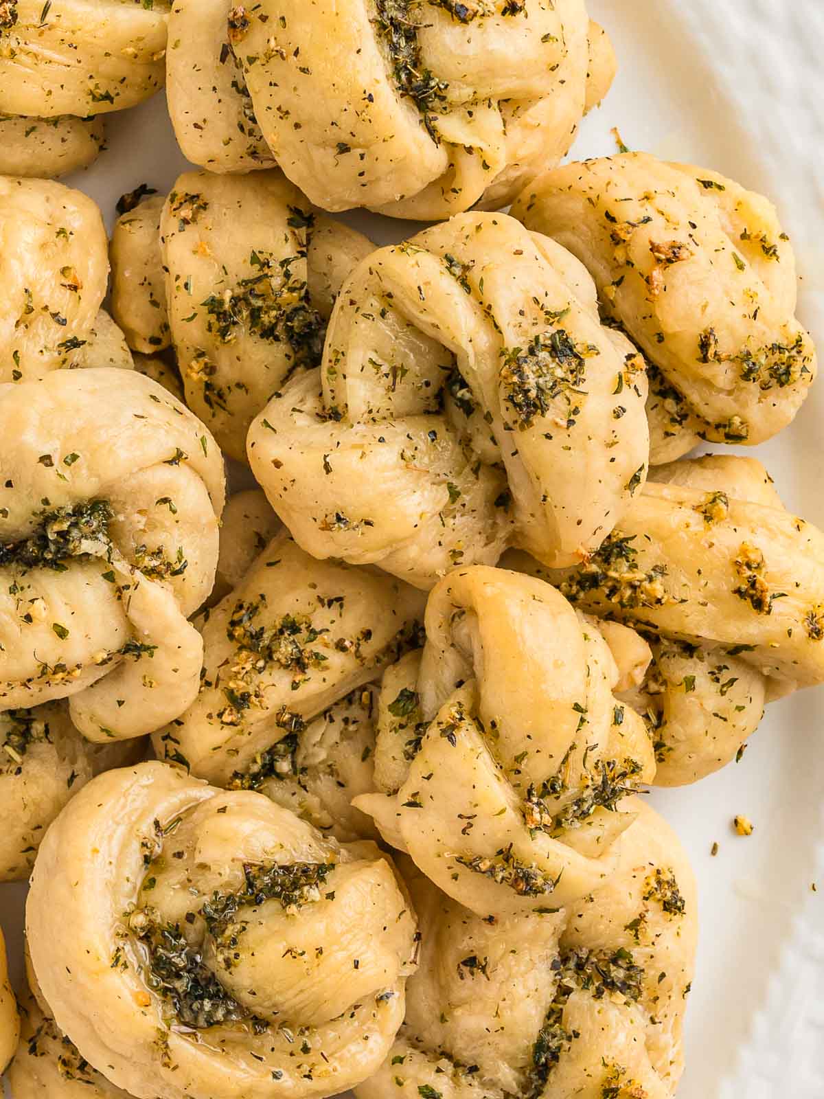 Up close of Homemade Garlic Knots on a white serving plate.