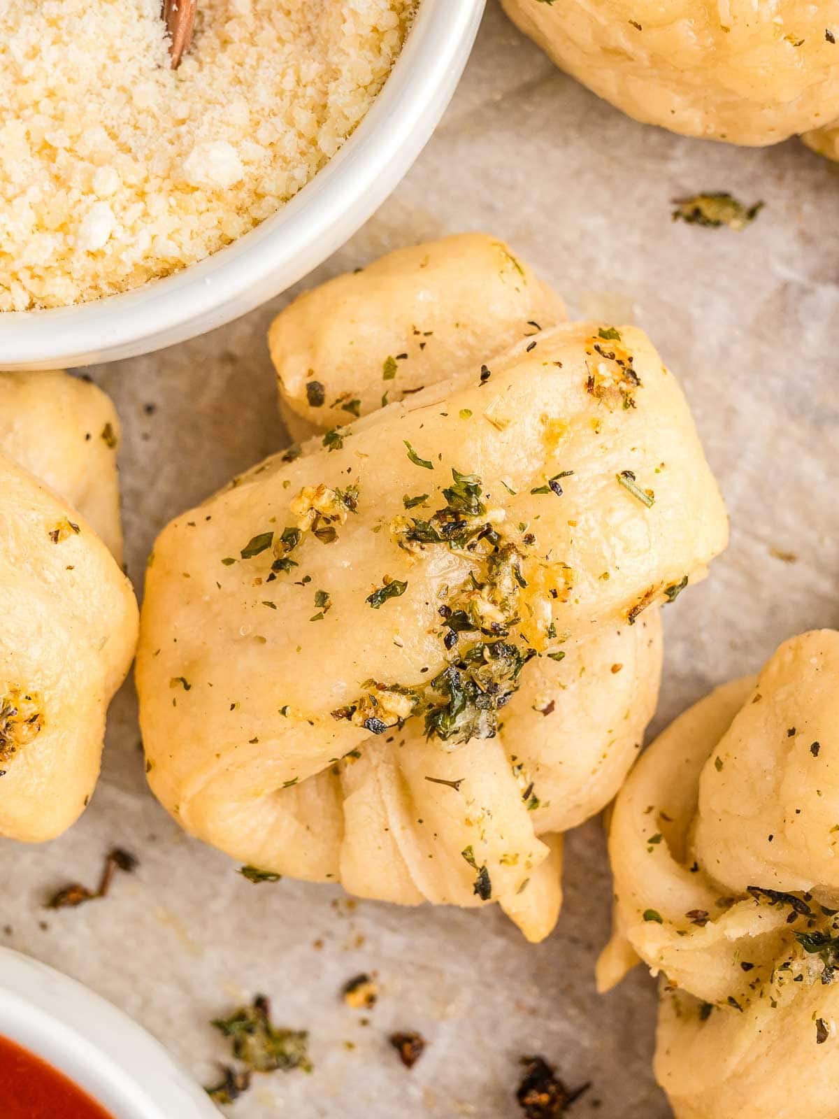 Up close of Homemade Garlic Knots with parmesan cheese in a bowl.