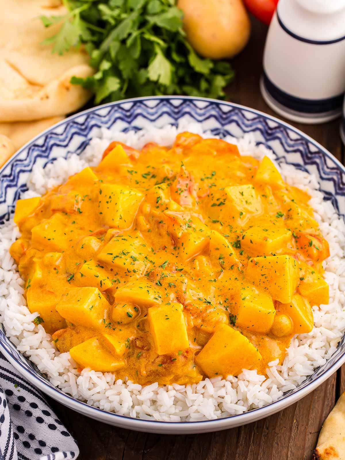 Potato Curry plated over rice on a wooden table.