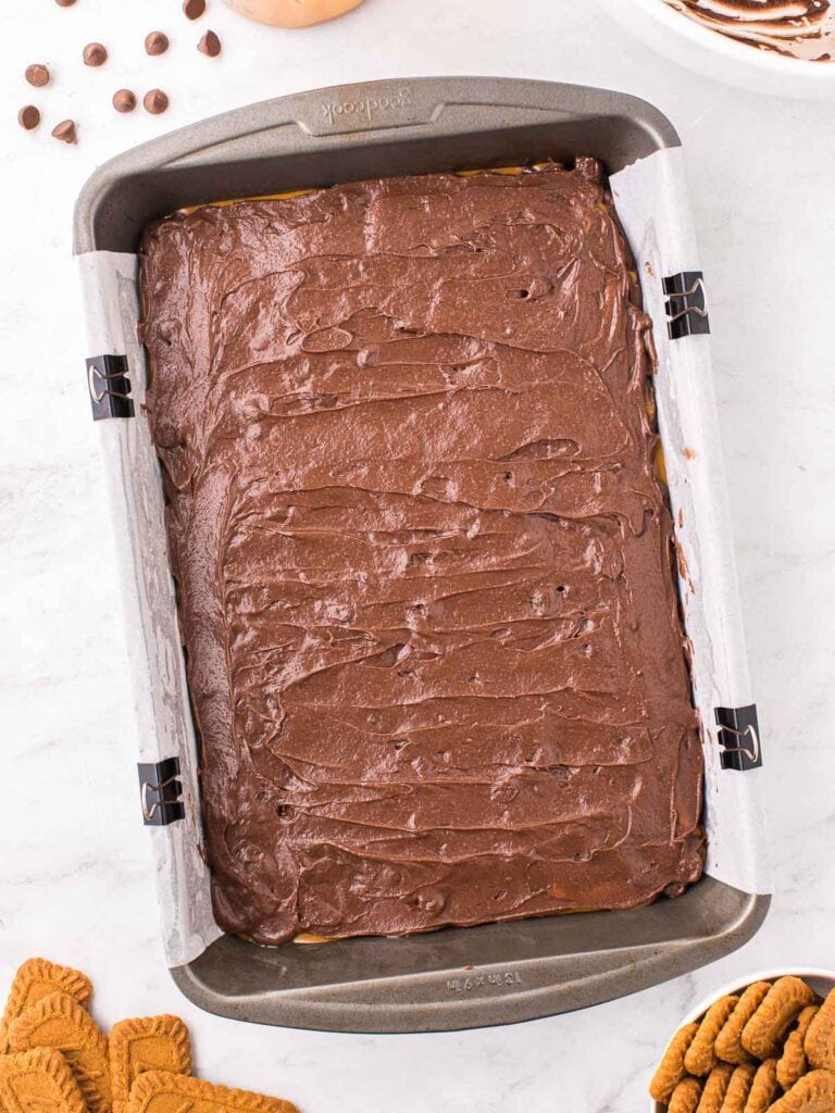 The remain Biscoff Brownie batter poured on top of the cookies spread in a 9x13 pan.