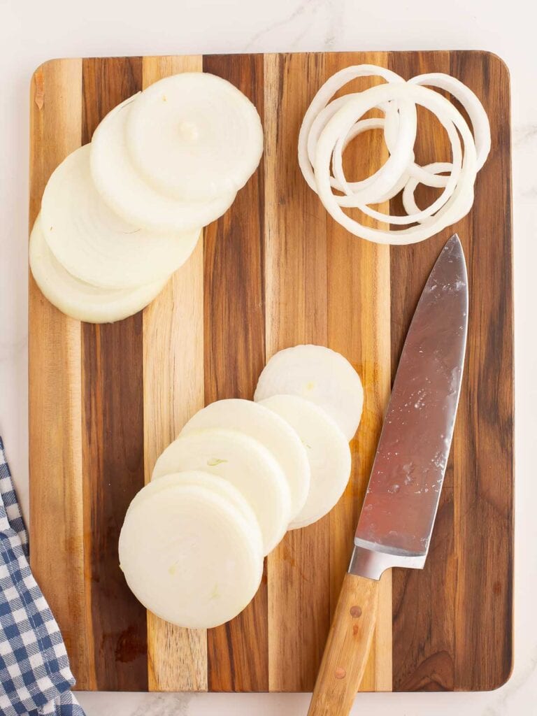 Sliced onions on a wooden board.