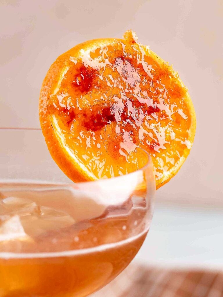 One slice of brûléed orange on the side of a glass.