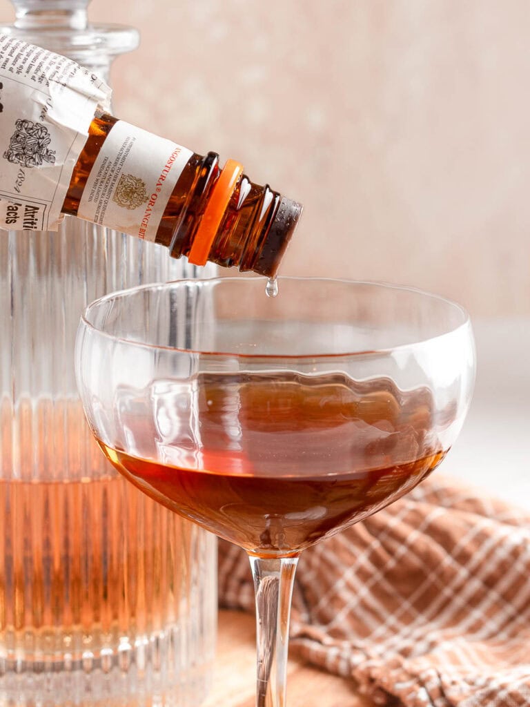 Orange bitters being poured into the Orange Cinnamon Old Fashioned Cocktail.