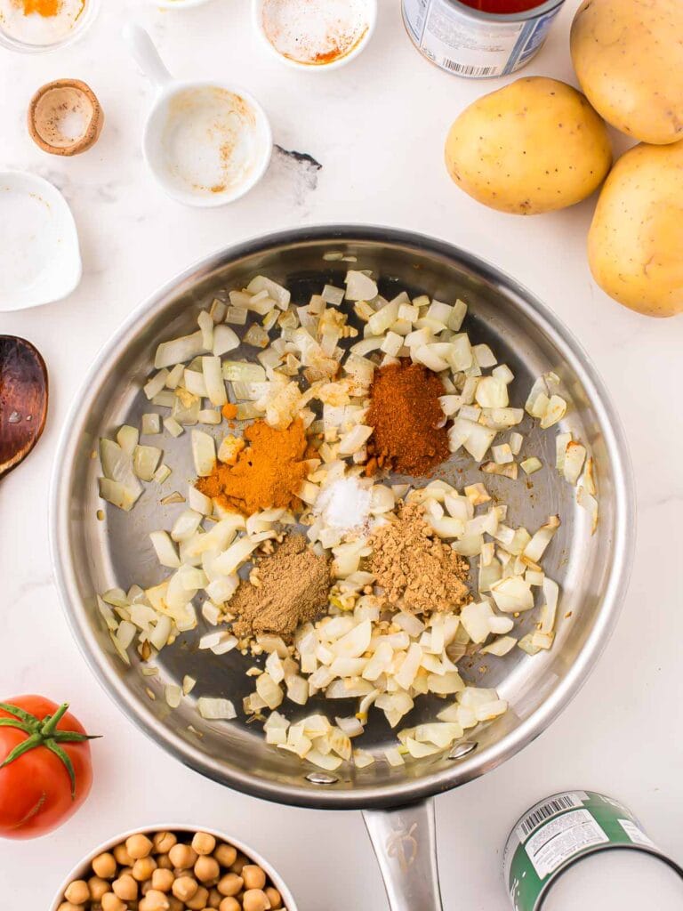 All the Potato Curry Spiced in a frying pan with the onions and garlic.