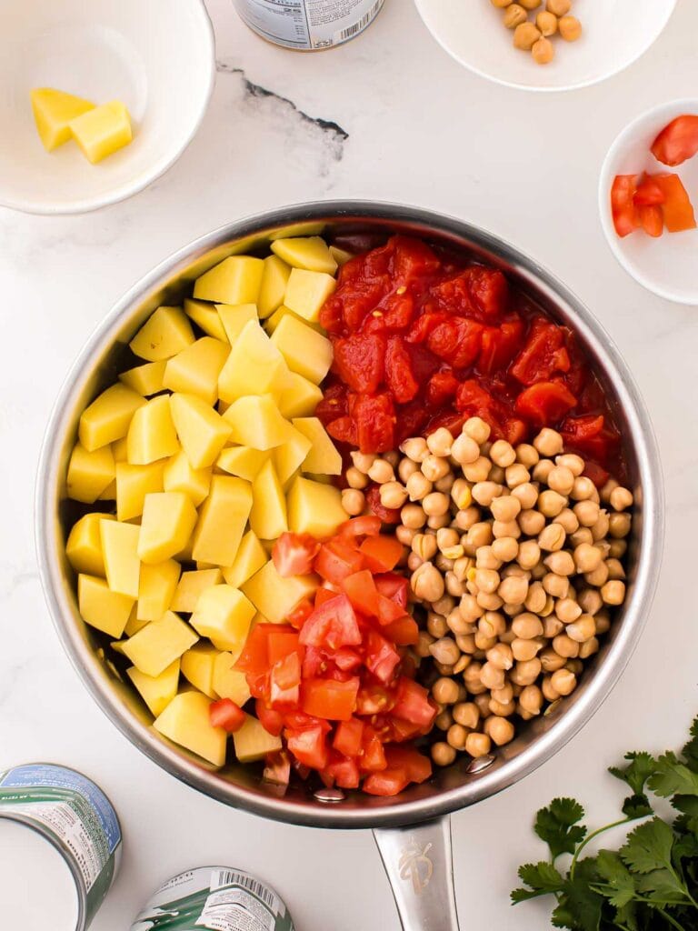 Potatoes, chickpeas and tomatoes add to the pan.