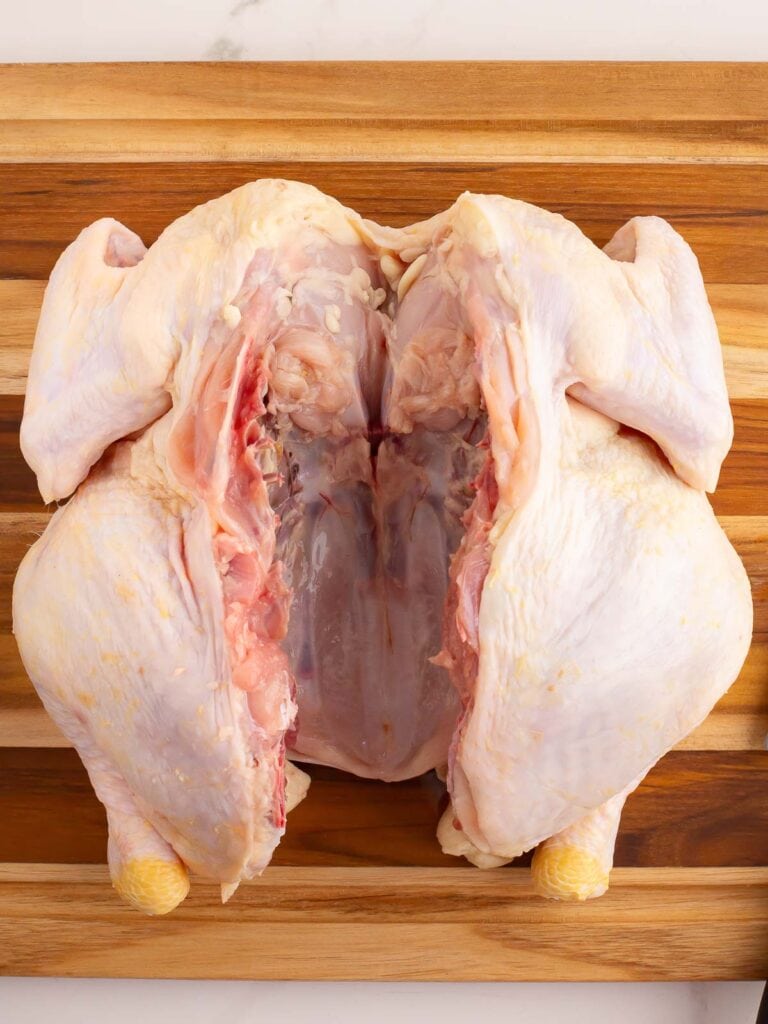 A raw chicken with the backbone removed.