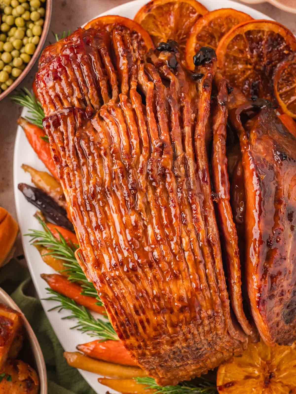 Up close overhead photo of Glazed Ham with roasted carrots and herbs.