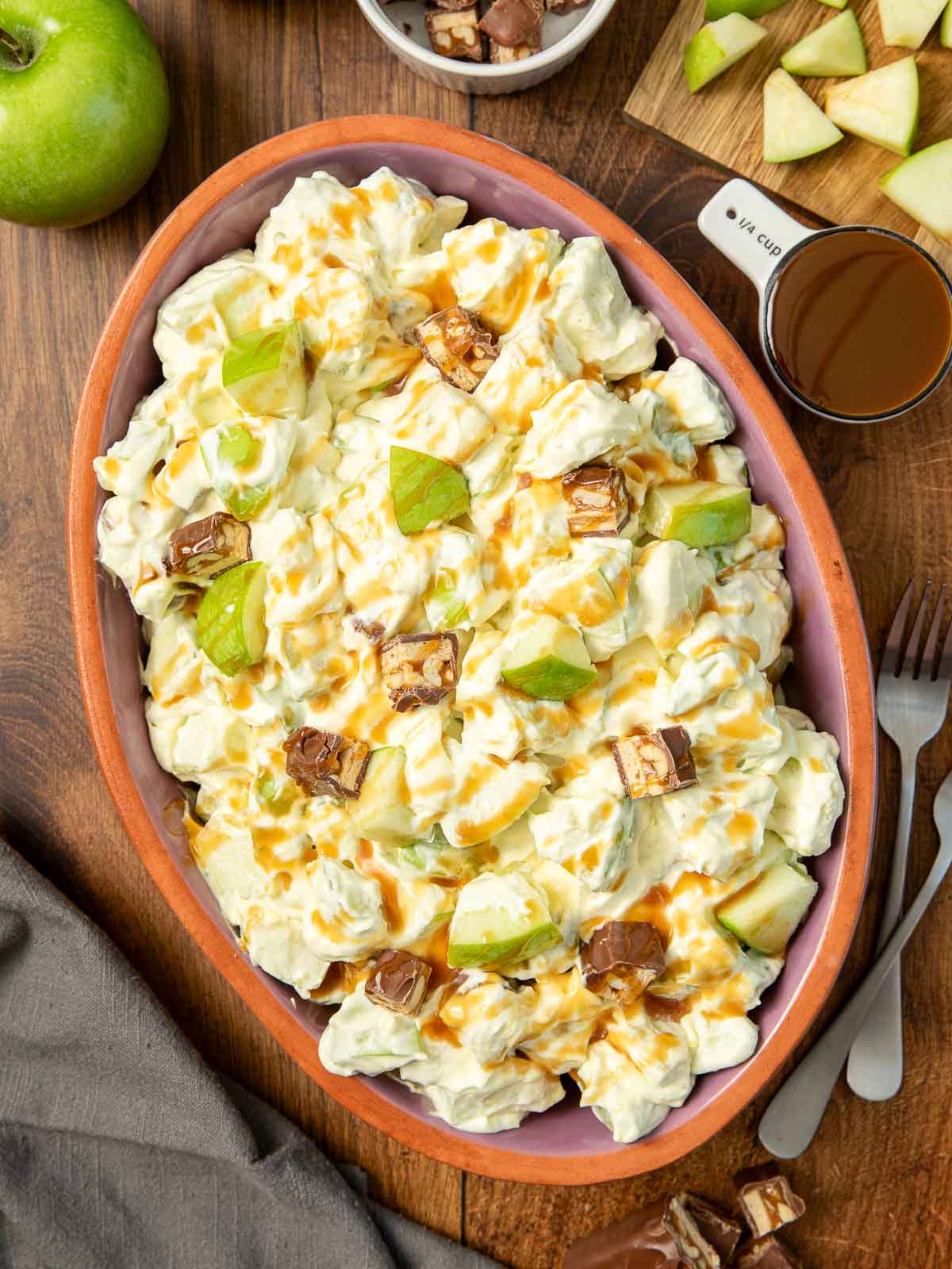 Snickers Salad in a serving bowl on a wooden table.